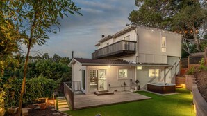 Une maison moderne à deux étages, dotée d’une terrasse, d’un jacuzzi et d’une pelouse bien entretenue.