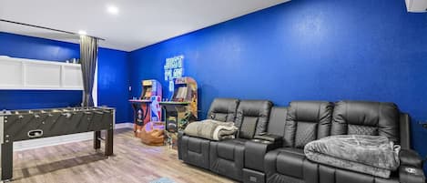 Une pièce équipée d’un baby-foot, d’un canapé et de jeux d’arcade.
