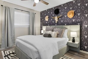 A bedroom with a bed, nightstands, a ceiling fan, and a wall with a cow skull and horns decoration. - Central Loc~Stylish~Pool~HotTub (San Antonio)