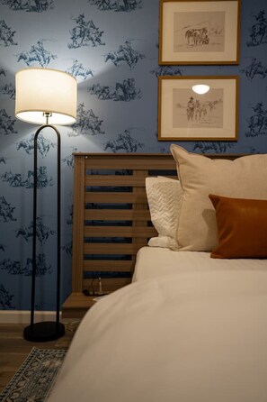 A bedroom with a bed, a nightstand, a lamp, and two framed pictures on the wall.