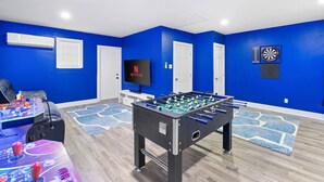 A room with a foosball table, a television, and a dartboard. - Central Loc~Stylish~Pool~HotTub (San Antonio)