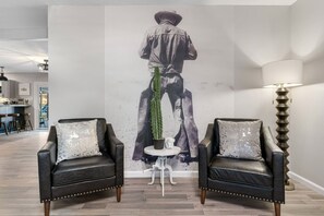 A modern living room with two leather armchairs, a small white table, and a large wall mural. - Central Loc~Stylish~Pool~HotTub (San Antonio)