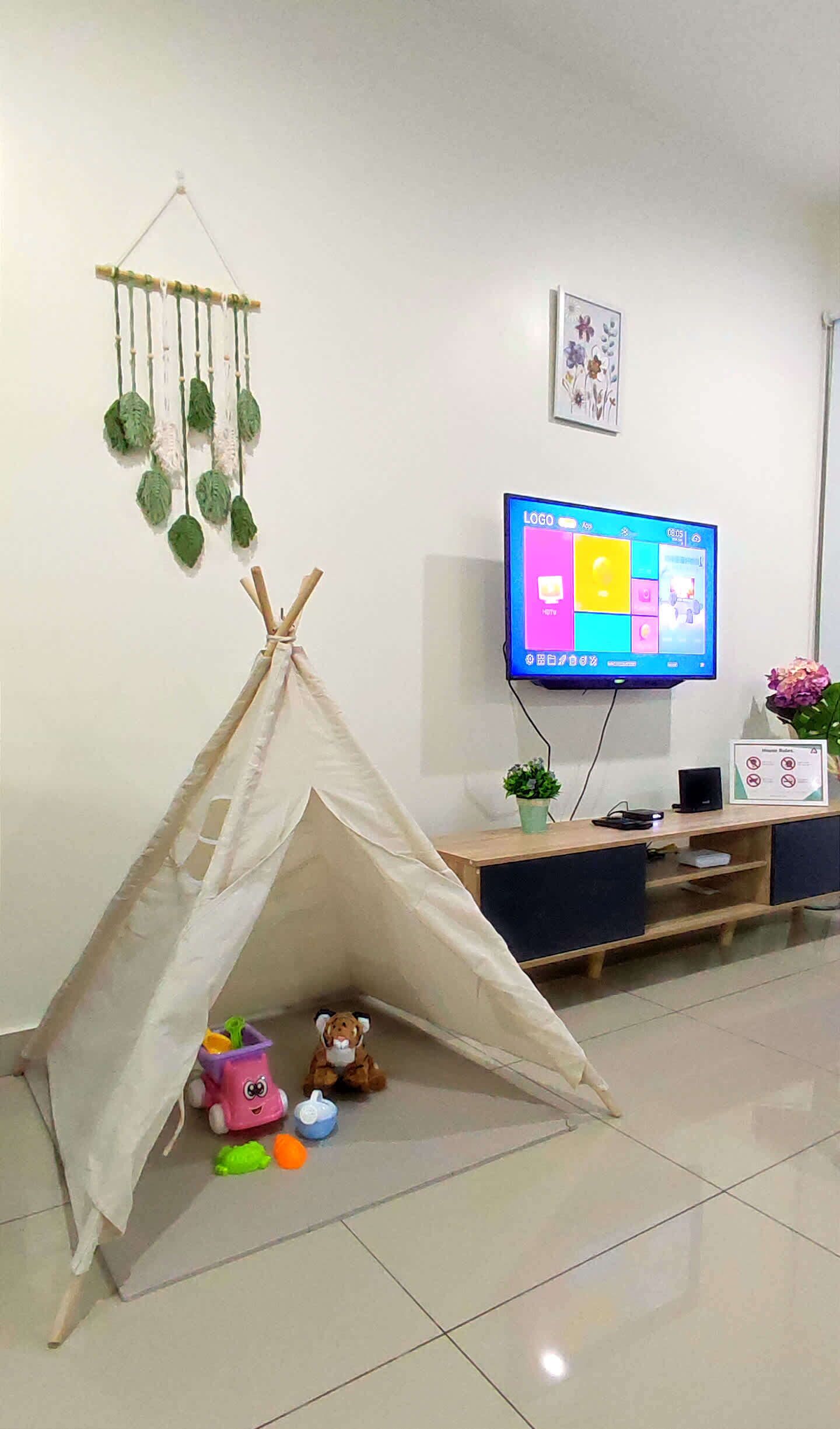 Un salon équipé d’un téléviseur, d’un petit espace de jeux et d’un élément décoratif fixé au mur.