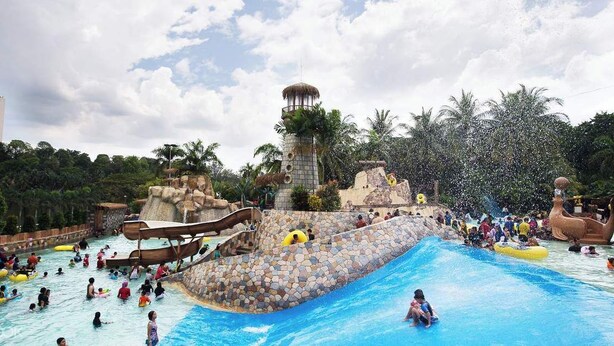 Ein Wasserpark mit großem Schwimmbecken, Rutschen und einem hohen Turm.