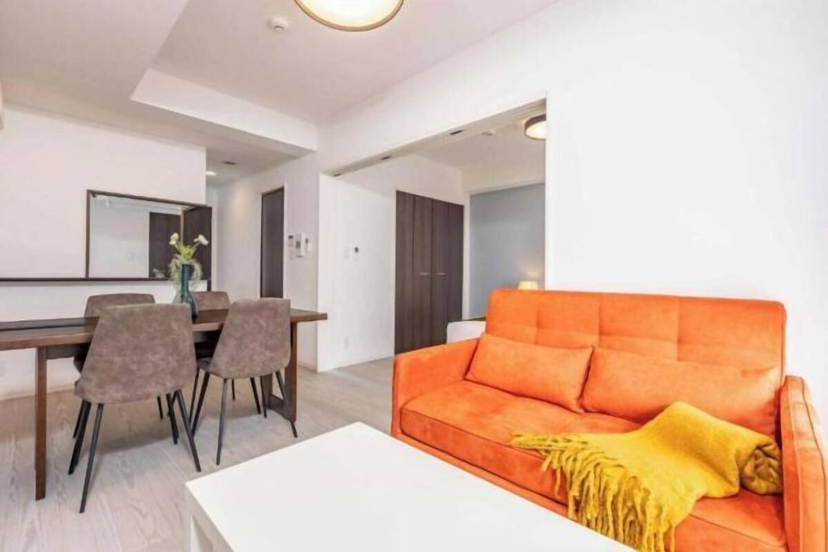 A modern living room with a sofa, a dining table with chairs, and a white coffee table.