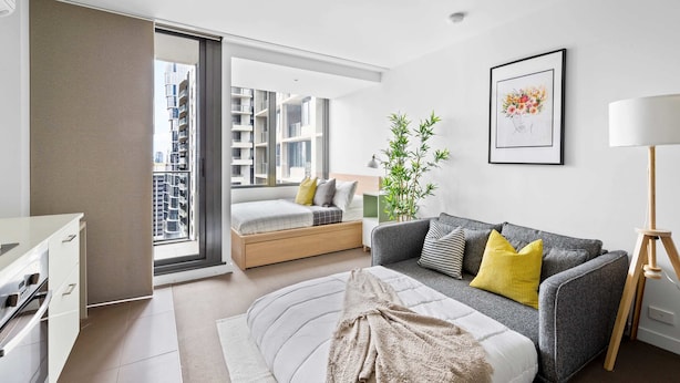 A modern apartment with a bed, sofa, and a dining area. - Cozy Studio Near Southern Cross With City Views (Melbourne)