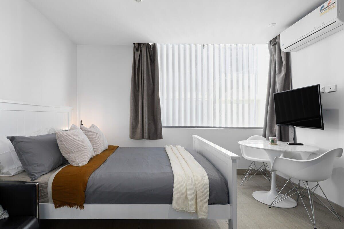 Ein modernes Hotelzimmer mit Bett, Nachttisch, Fernseher und Schreibtisch mit Stühlen.