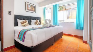 Quarto de hotel com uma cama grande, cabeceira, janela com cortinas e um quadro na parede.