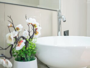 A bathroom with a white sink, a modern faucet, and a decorative orchid arrangement. - Inkary Hotel Machupicchu  (Machu Picchu)