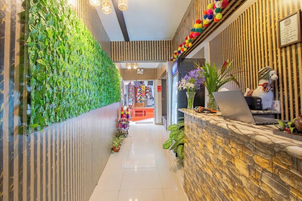 A reception area with a green vertical garden, a stone reception desk, and a colorful decorative wall. - Inkary Hotel Machupicchu  (Machu Picchu)