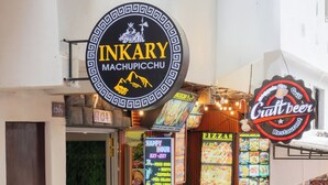 Um restaurante chamado Inkary, com um letreiro de cerveja artesanal, um quadro de cardápio e uma área de estar verde.