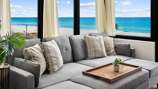 A gray sofa with multiple cushions, a wooden tray, and a potted plant. - Beachfront 2BR! · Sunbird 3rd Floor! Free Beach Chairs & Umbrella Service! (Panama City Beach)