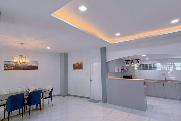 Une cuisine moderne dotée d’un îlot central, d’un éclairage encastré au plafond et d’un coin repas avec une table et des chaises.