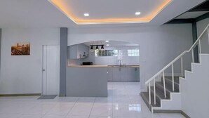 A modern kitchen with a central island, recessed ceiling lights, and a staircase to the right. - Anjia Serene Pool Villa (Pattaya)