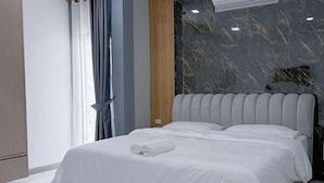 A modern hotel room with a large bed, a marble accent wall, and a window with curtains. - Anjia Serene Pool Villa (Pattaya)
