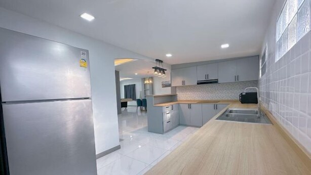 A modern kitchen with stainless steel appliances, light wood countertops, and grey cabinets. - Anjia Serene Pool Villa (Pattaya)
