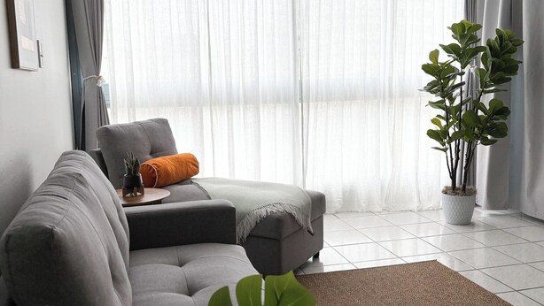 A modern living room with a grey sectional sofa, a small table with a plant, a potted plant, and a ceiling fan. - Modern Condo in Condado - Walk to Beaches, Restaurants & Nightlife (san juan)