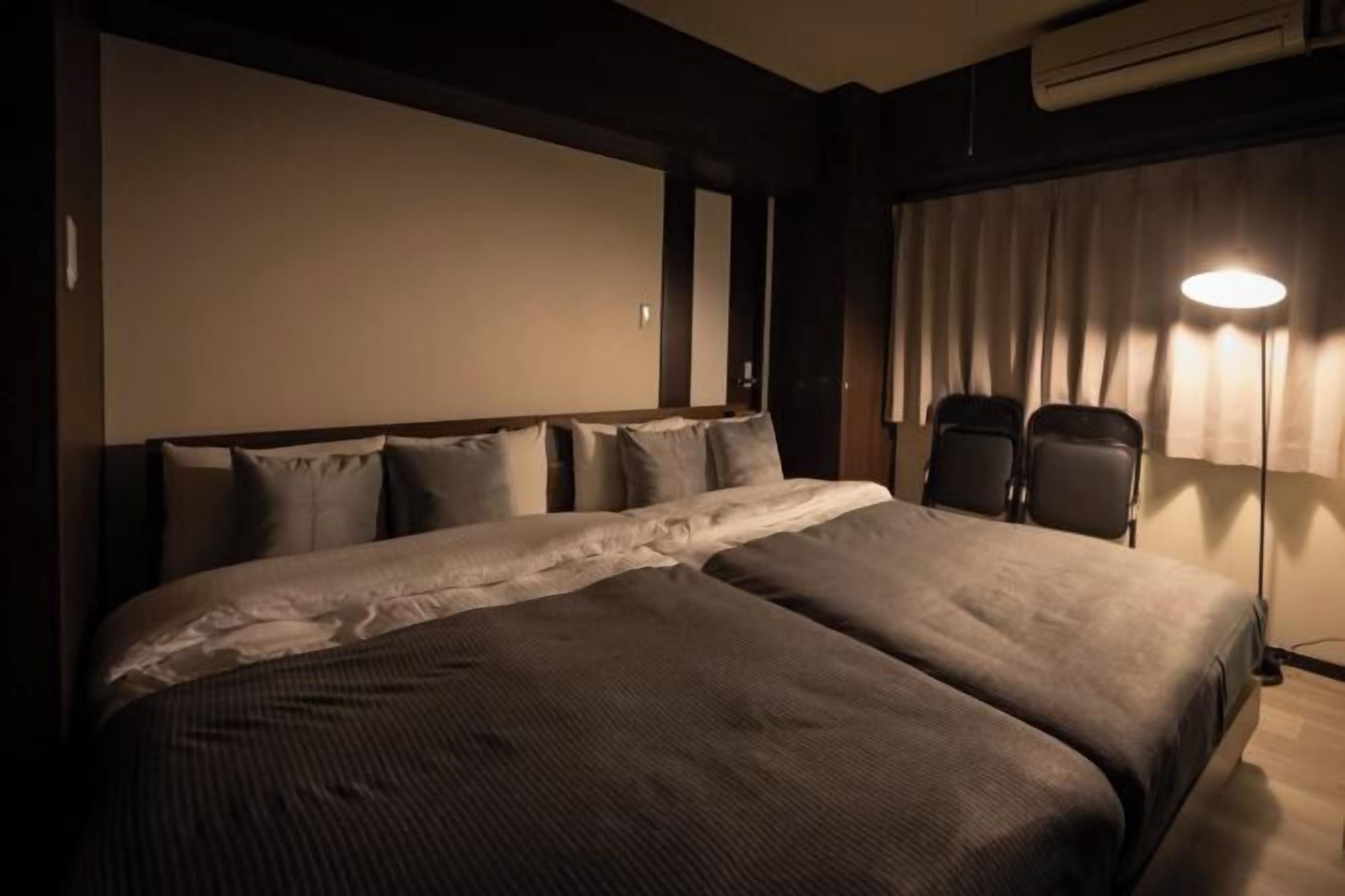 Habitación de hotel con una cama grande, dos sillas, un televisor de pantalla plana y un equipo de aire acondicionado.