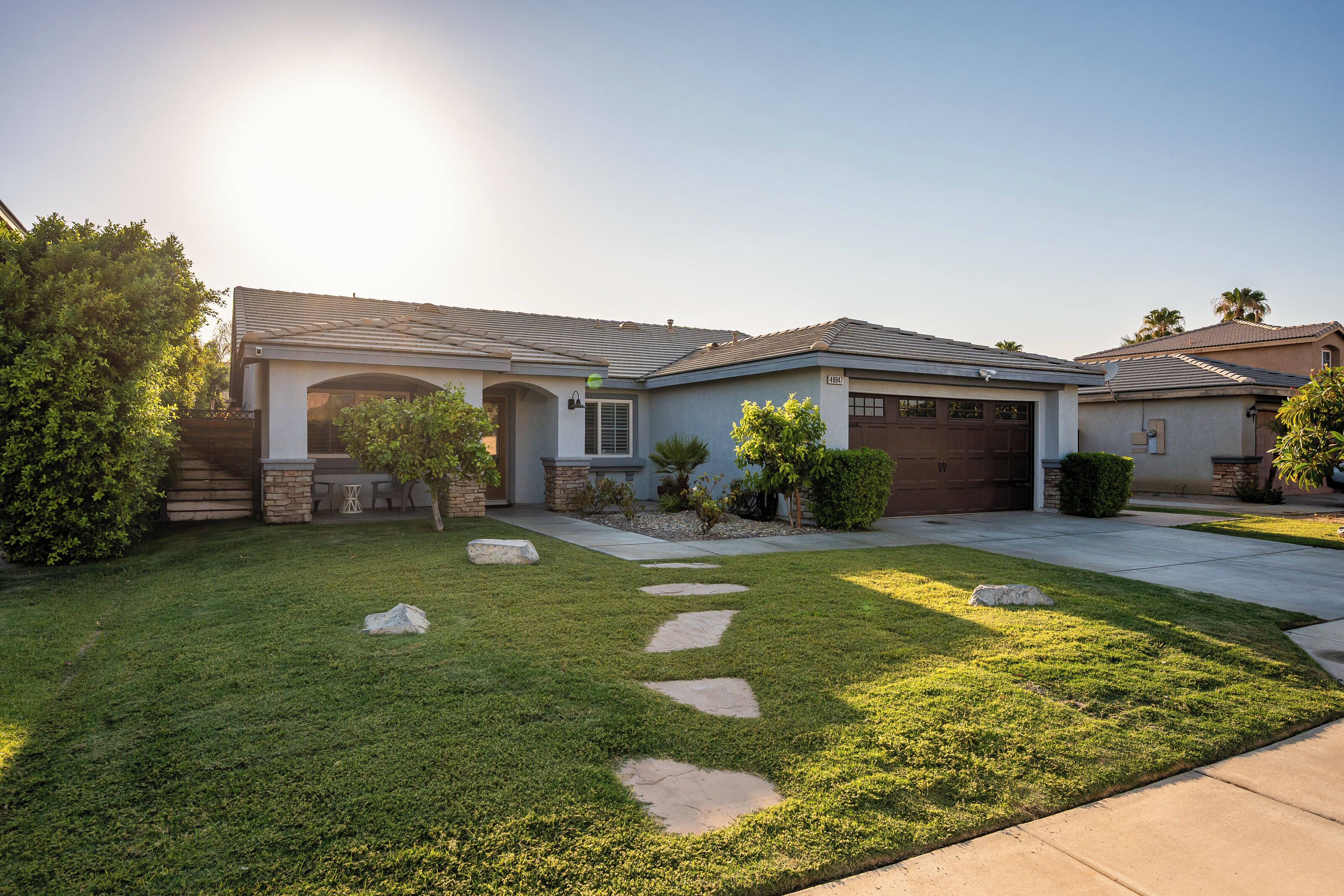 A residential house with a well-maintained lawn, stone stepping stones, and a garage.
