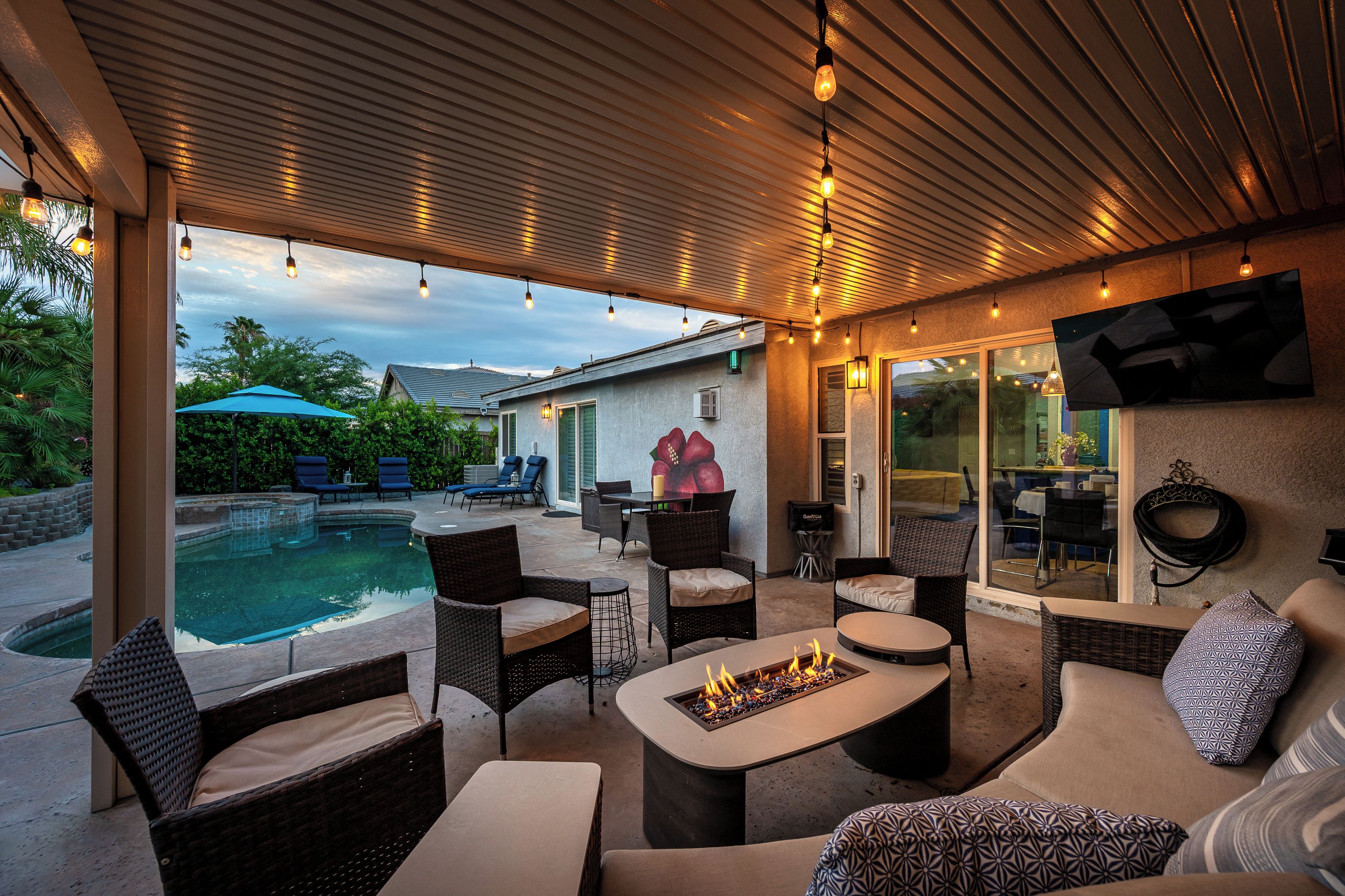 An outdoor patio with a pool, seating, and a fire feature.