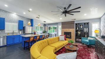 A modern kitchen with blue cabinets, a yellow sofa, and a fireplace.