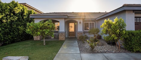 A residential house with a front entrance, a driveway, and surrounding greenery.