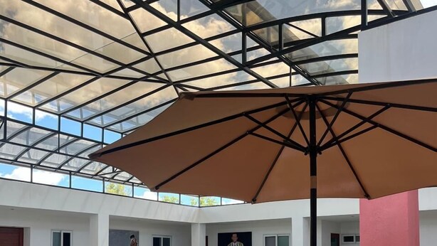 An indoor swimming pool with a glass ceiling, lounge chairs, and a table with a vase of flowers. - Rosa y Oro Hotel Boutique (Jesús María)
