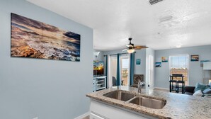 A kitchen with a granite countertop, double sink, and a ceiling fan. - Gulf Island 232 - Sunset Suite (Navarre)