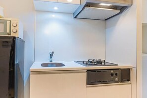 A compact kitchen with a built-in gas stove, a sink, and a microwave.