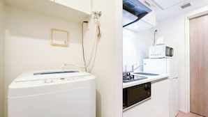A compact kitchenette with a washing machine, microwave, and oven.