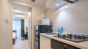 A compact kitchen with a stove, microwave, and refrigerator.