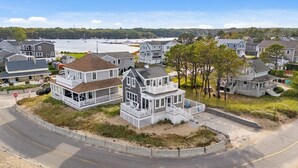A coastal residential area with houses featuring prominent porches and large windows, likely offering views of the nearby water.