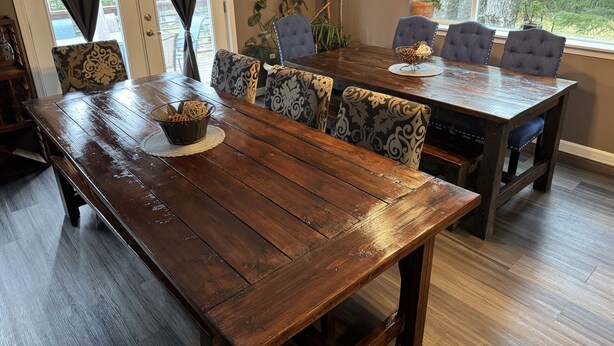 A wooden dining table with patterned chairs, a woven basket, and a window with a view of trees. - Bear Bottoms at Salmon Creek (Seward)
