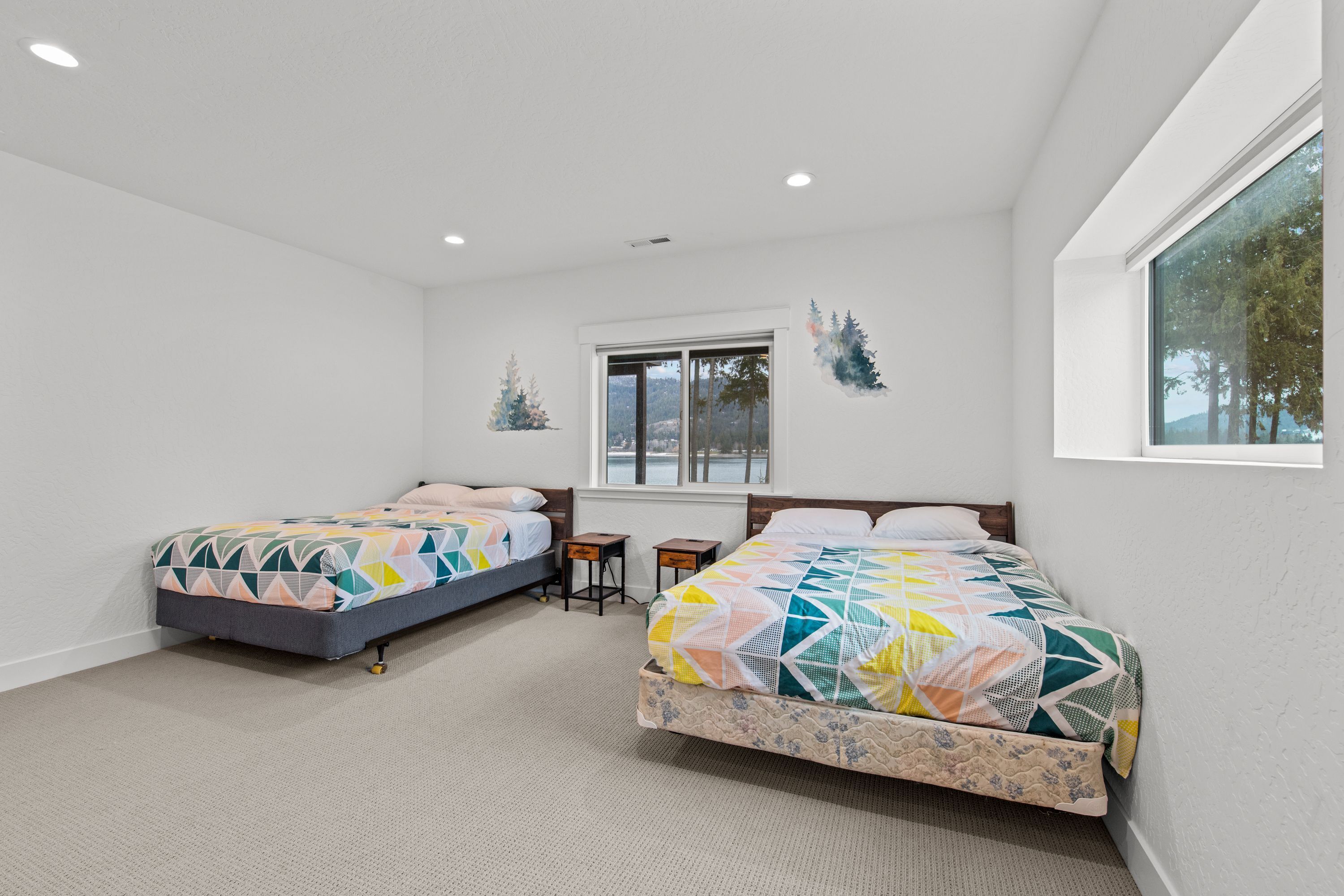 A bedroom with two beds, a window, and a small desk.