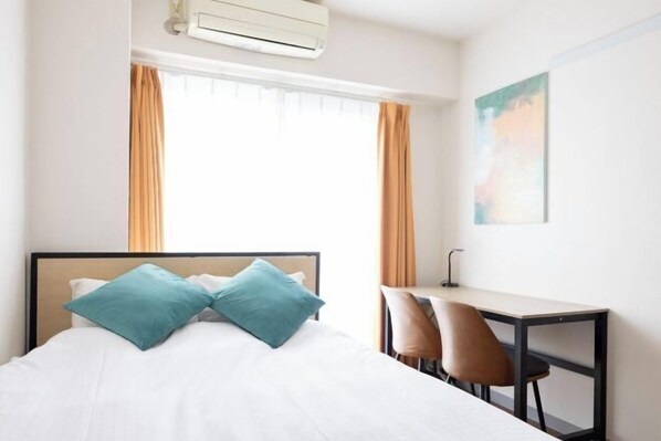 A hotel room with a bed, a desk, and two chairs.