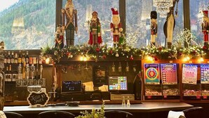 A bar area with a view of snow-capped mountains, decorated with Christmas ornaments and chandeliers.