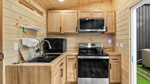 A compact kitchen with wooden cabinets, a stainless steel stove, a microwave, and a sink. - Upstairs Room · Mountain View with Hot Tub & Sauna (Eastmont)