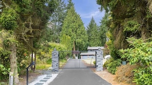 A gated driveway leading to a house with a stone gate and a mailbox. - Crystal Dome · Private Glamping Dome w/ Hot Tub, Sauna & Panoramic View (Eastmont)