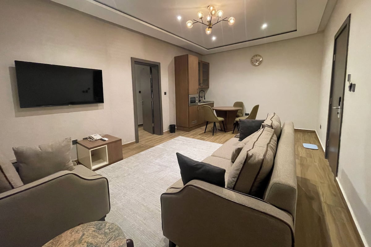 Un salon moderne doté d’un téléviseur à écran plat, d’un canapé, d’une table basse et d’un coin repas avec des chaises et une table.