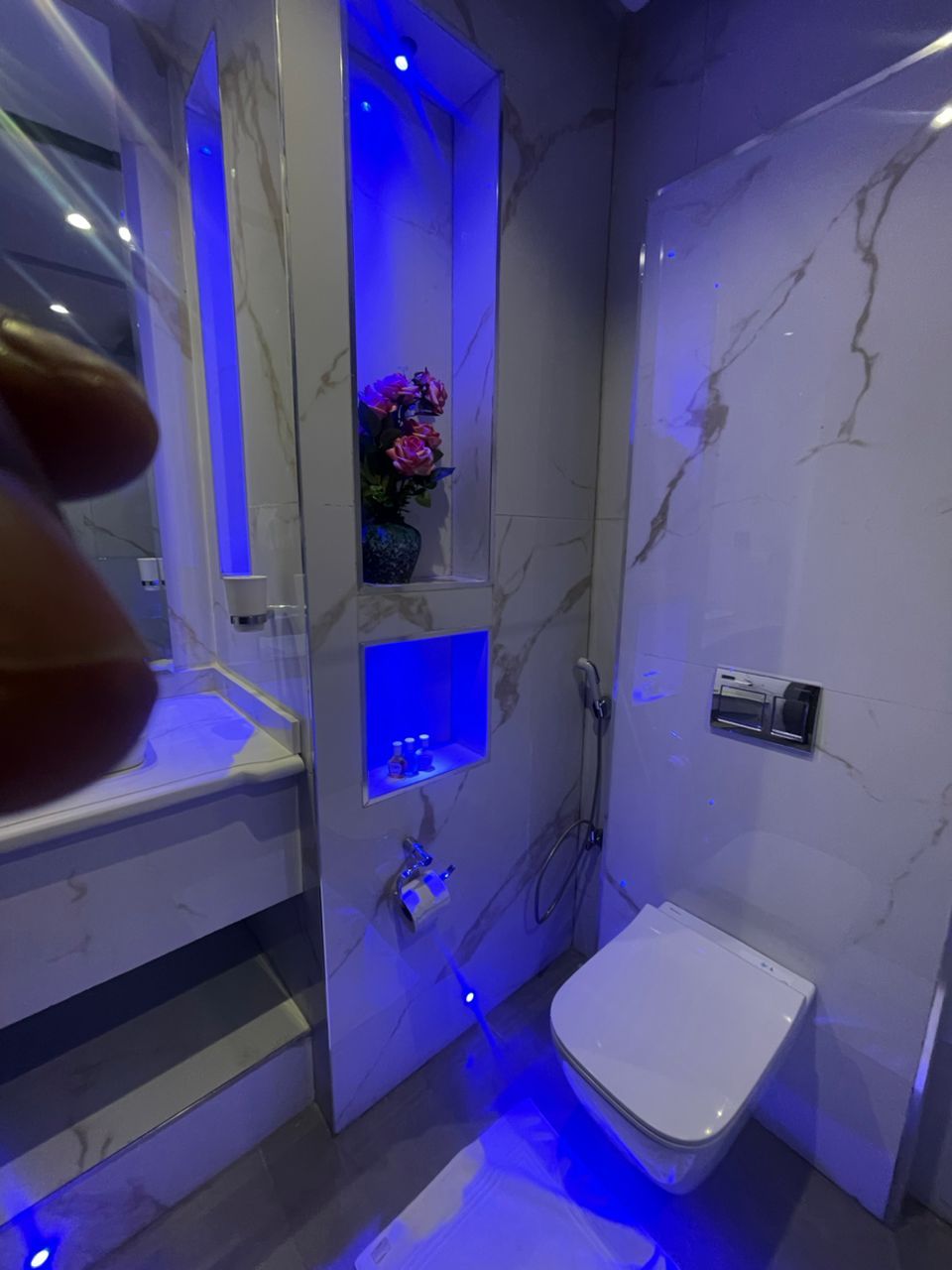 A modern bathroom with a marble wall, a built-in shower, and a toilet.