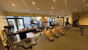 Un gimnasio con cintas de correr, máquinas de pesas y una banca.