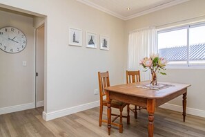 Uma sala de jantar com uma mesa de madeira, cadeiras, um relógio e quadros nas paredes.