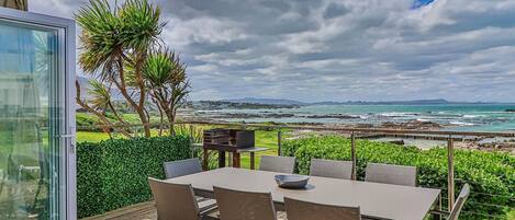 A patio with a table and chairs, overlooking a coastal landscape.