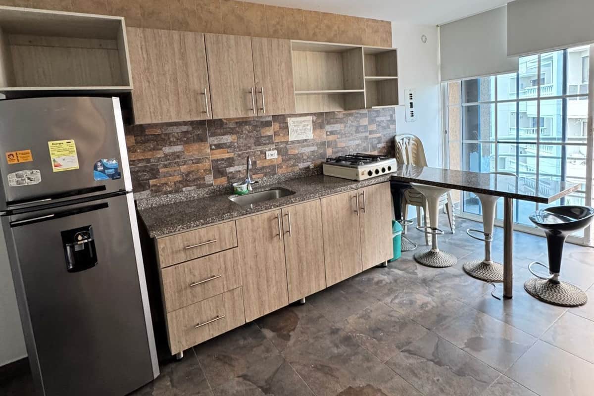 A modern kitchen with a built-in refrigerator, a gas stove, and a ceiling fan.