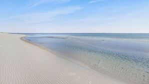 A beach with clear water and a wide sandy shore. - 1 BLOCK to the BEACH! Weekly/Monthly promotions! Bay views! Dog friendly! (Gulf Shores)