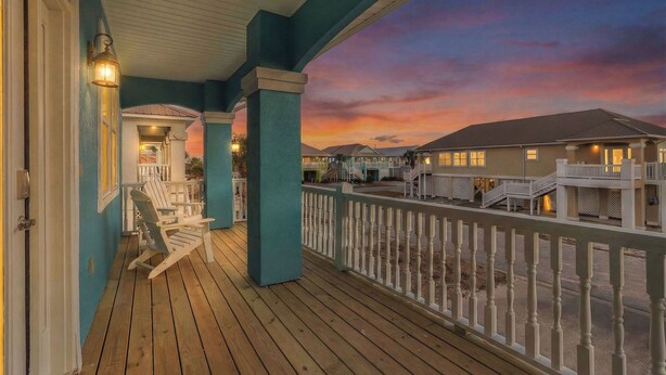 A wooden deck with Adirondack chairs, a railing, and a sunset view. - 1 BLOCK to the BEACH! Weekly/Monthly promotions! Bay views! Dog friendly! (Gulf Shores)