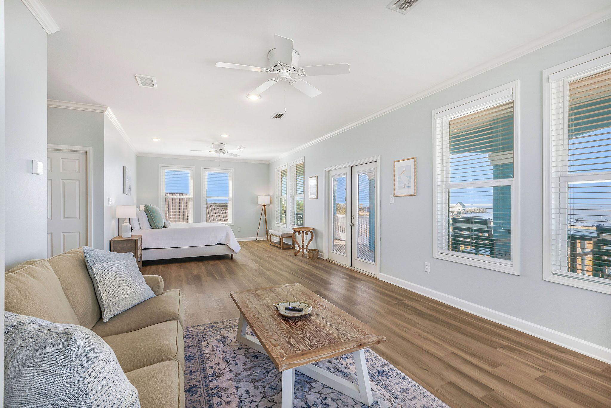 A spacious living room with a sofa, a coffee table, and a bed in the background.