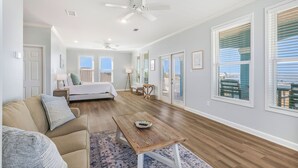 A spacious living room with a sofa, a coffee table, and a bed in the background. - 1 BLOCK to the BEACH! Weekly/Monthly promotions! Bay views! Dog friendly! (Gulf Shores)
