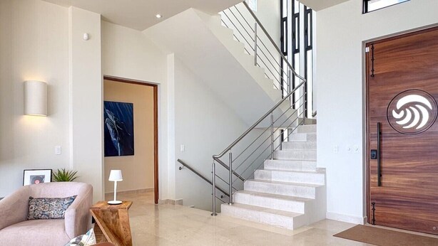 Ein modernes Interieur mit Treppe, einer Couch und einer Holztür mit kreisförmigem Dekor.