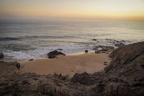 Un paisaje costero con una playa arenosa, afloramientos rocosos y el océano.